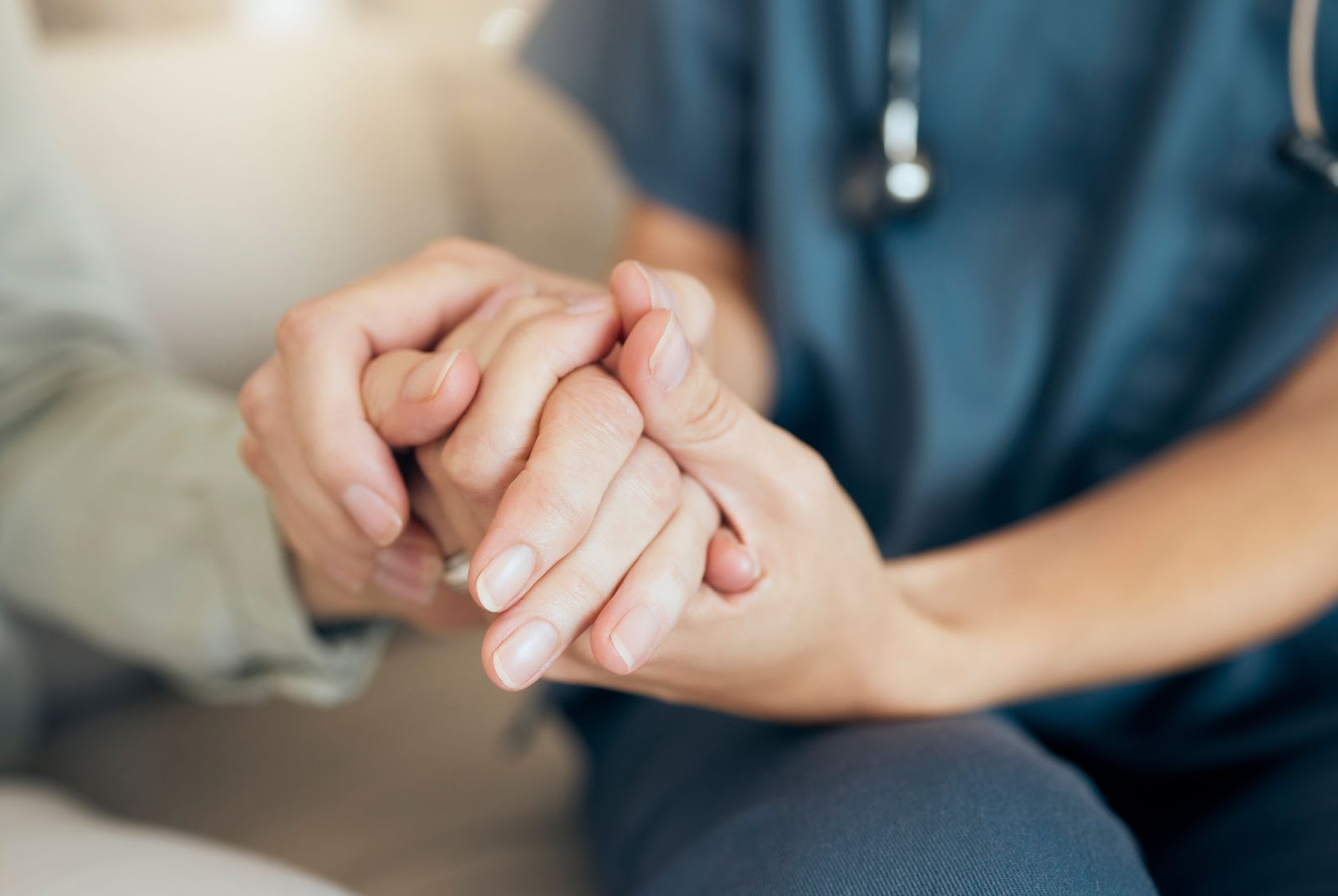 a close-up photo of a caregiver holding the hand of a senior as they transition into their assisted living community