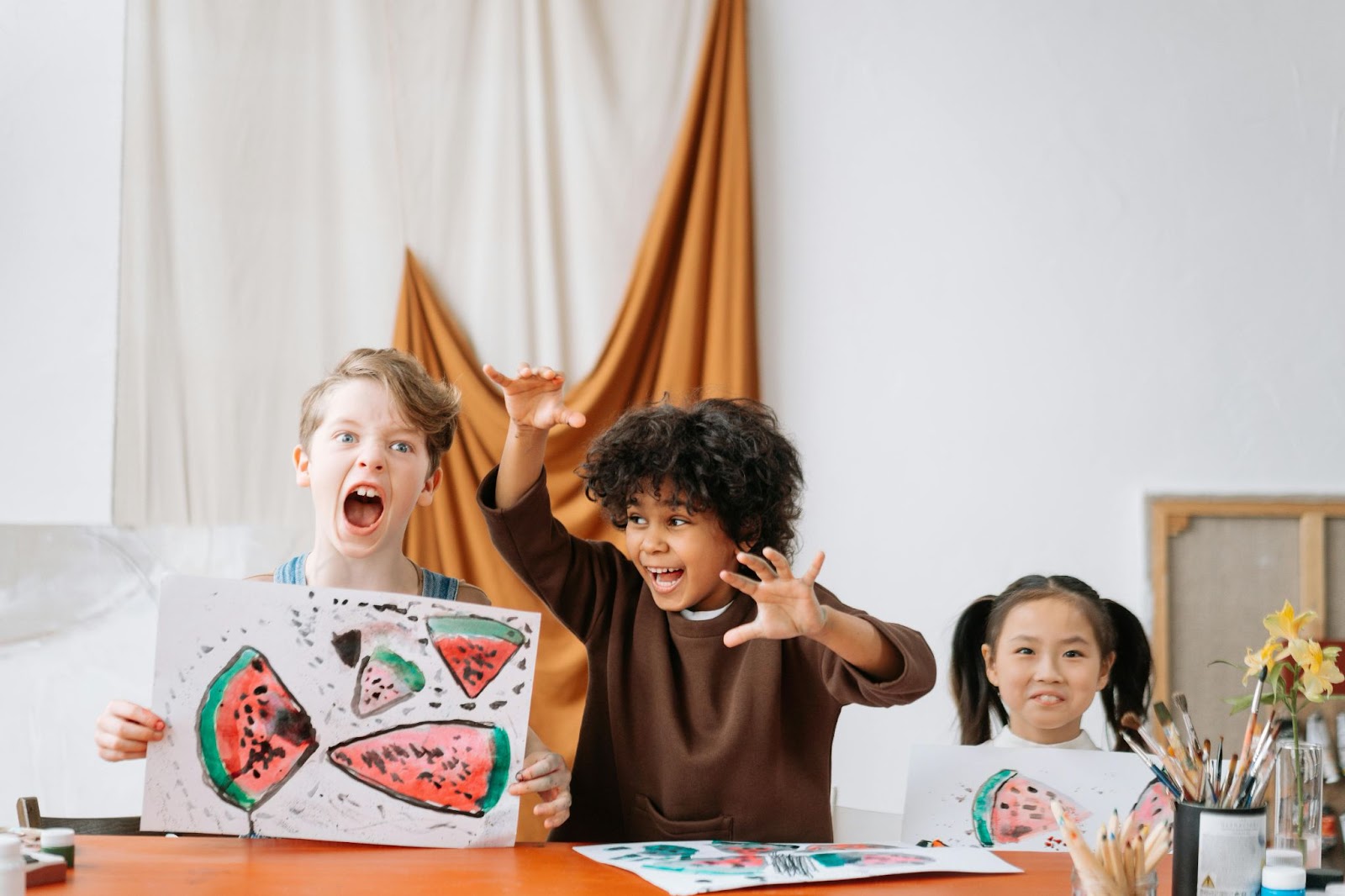 Three young students having fun drawing watermelons in a class