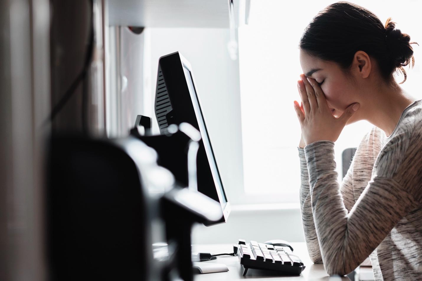 Stressed woman facing computer