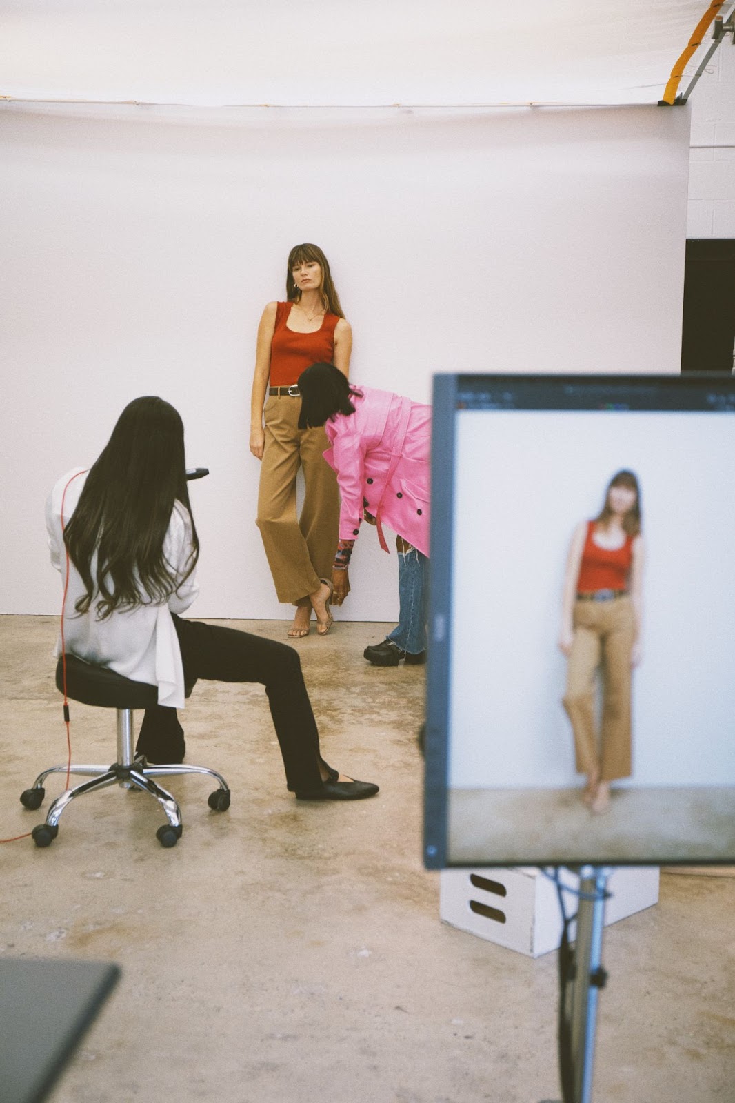 Model being styled on set with a stylist making adjustments to her outfit during an e-commerce photoshoot.