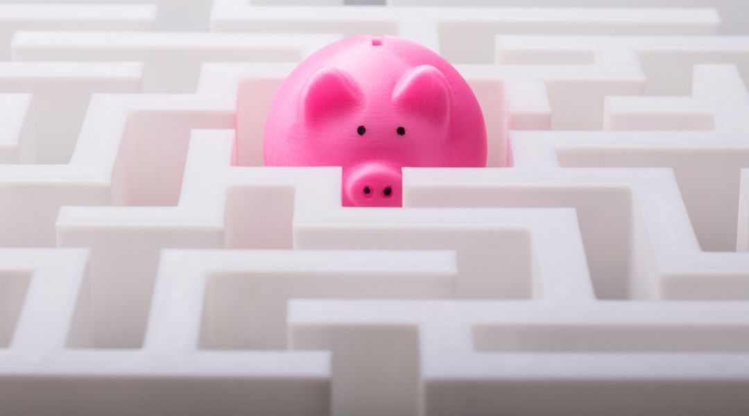 A bright pink piggy bank peeking out from the center of a complex white maze.