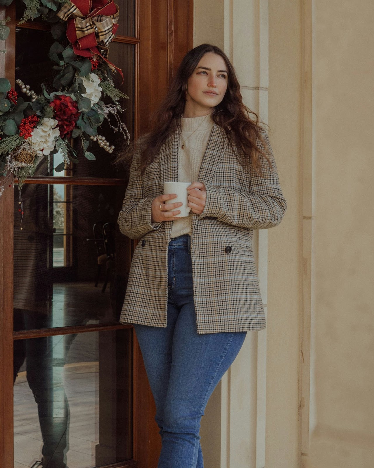 A lady standing for a professional headshot wearing warm tone clothes