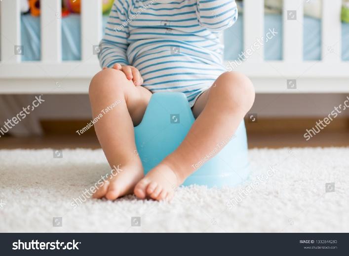 Cute toddler boy, potty training, playing with his teddy bear on potty