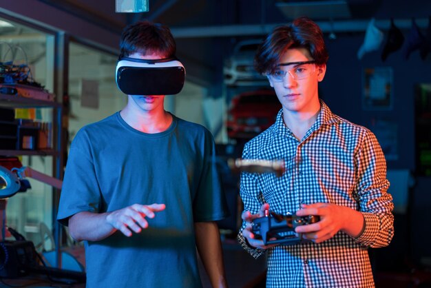 Teens doing experiments in robotics in a laboratory Boy in protective glasses and guy in VR headset