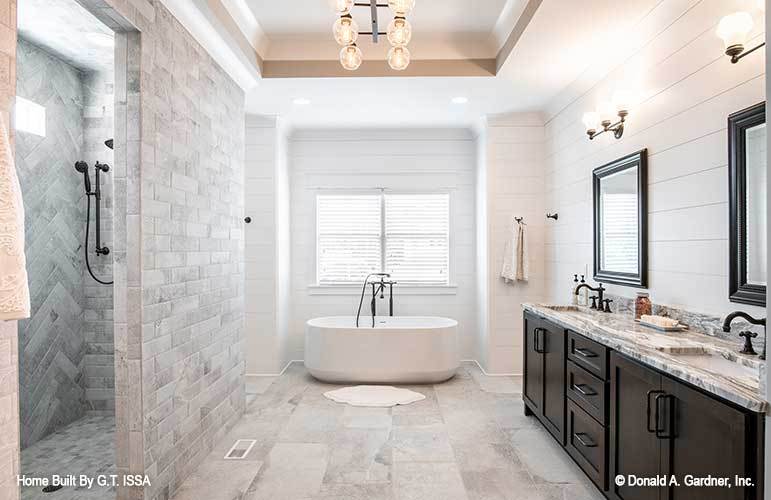 The primary bathroom offers a walk-in shower, a freestanding tub, and a dual sink vanity fitted with wrought iron fixtures.