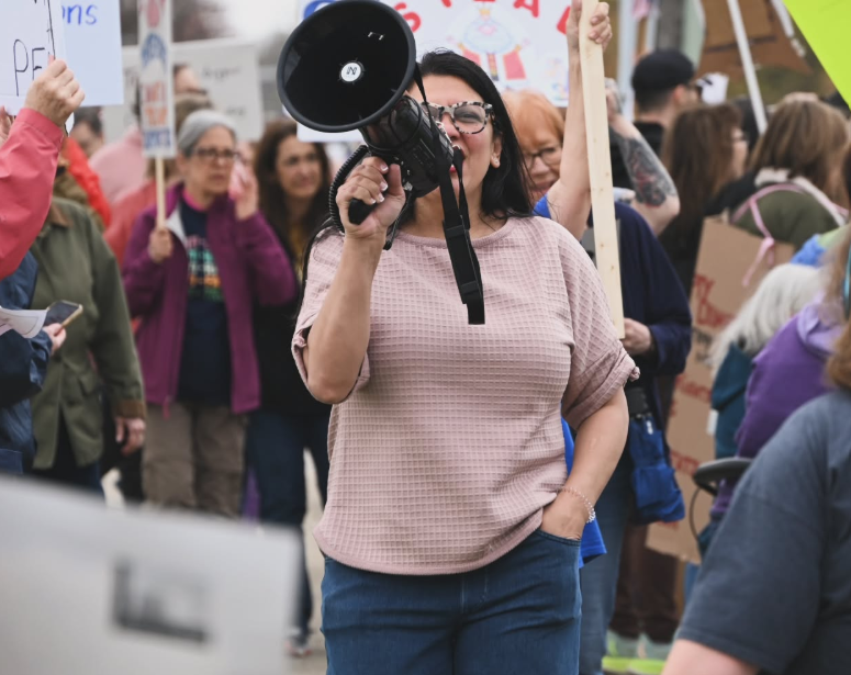Rashida stands holding a bullhorn in a rally