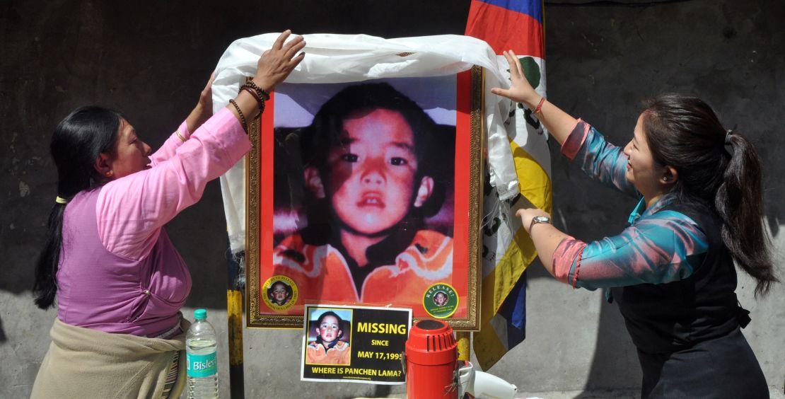 Tibetans stand next to a portrait showing the last know image of Gedhun Choekyi Nyima, on April 25, 2017 in Mcleodganj near Dharamsala, India. 