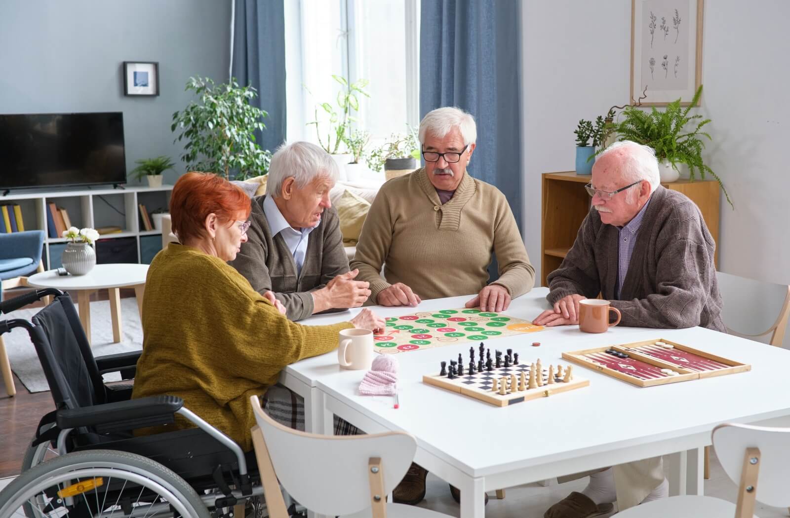 A few seniors sit around a table with several board games prepared for an afternoon of fun.