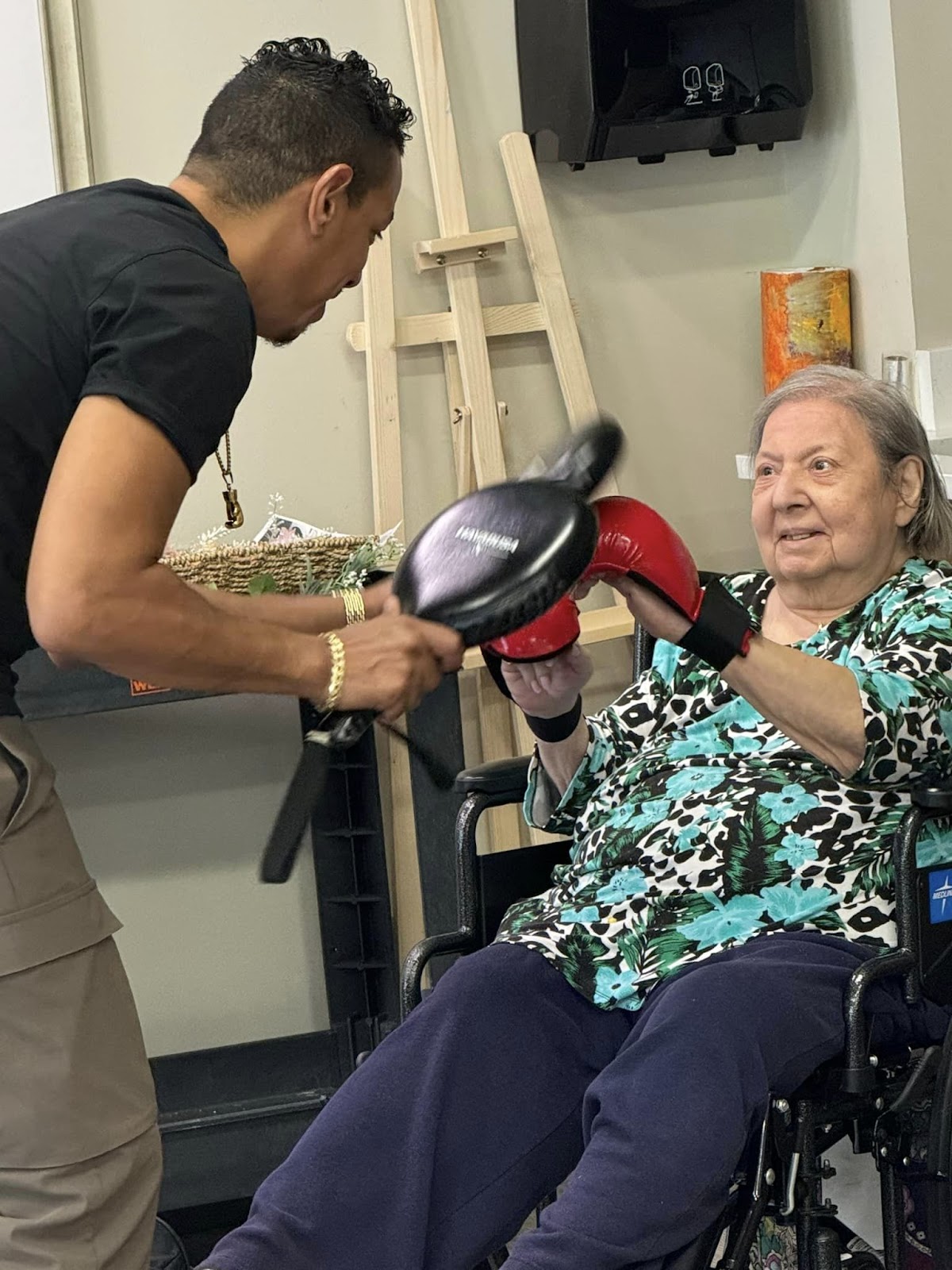 A senior shadow boxing in a wheelchair with an occupational therapist