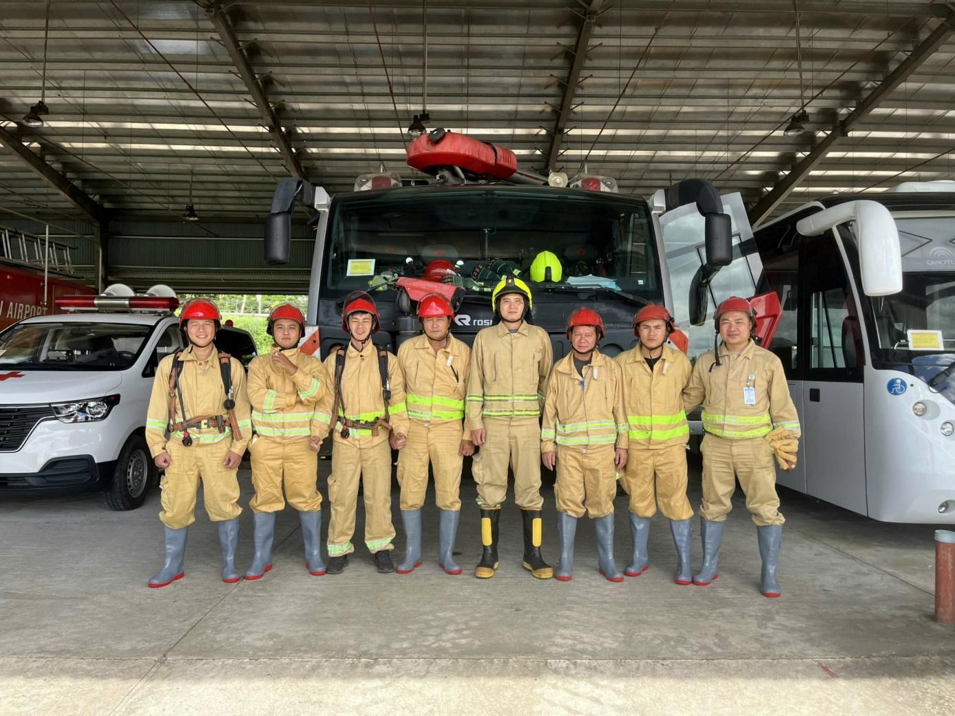 A group of firefighters standing in front of a truckDescription automatically generated