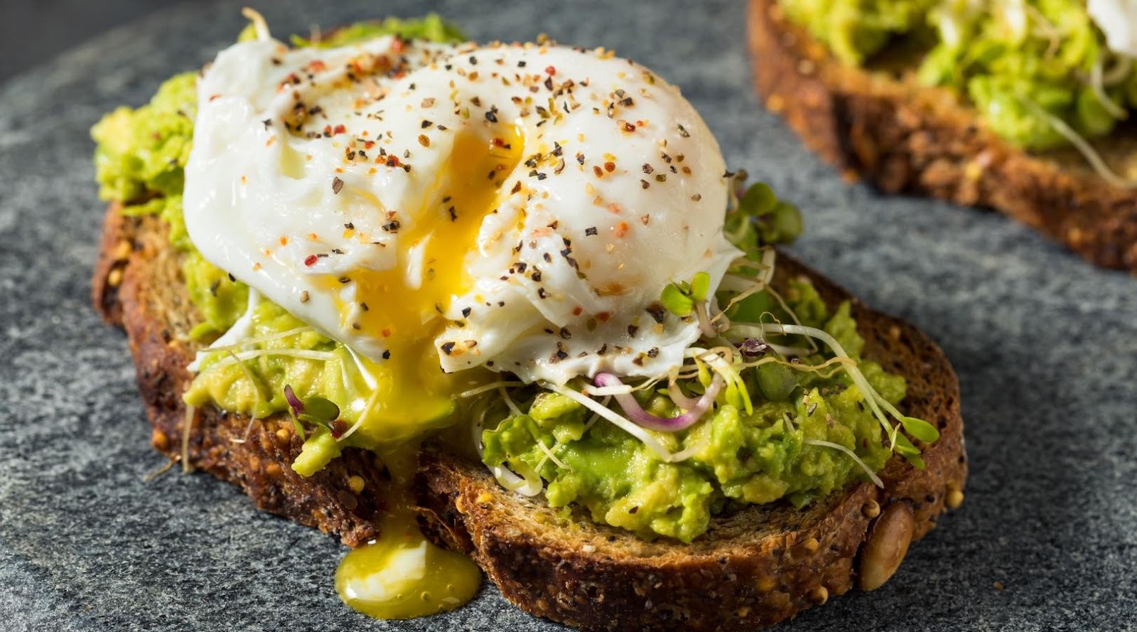 Avocado toast topped with a poached egg, microgreens, and black pepper, a popular healthy breakfast in Kanata.