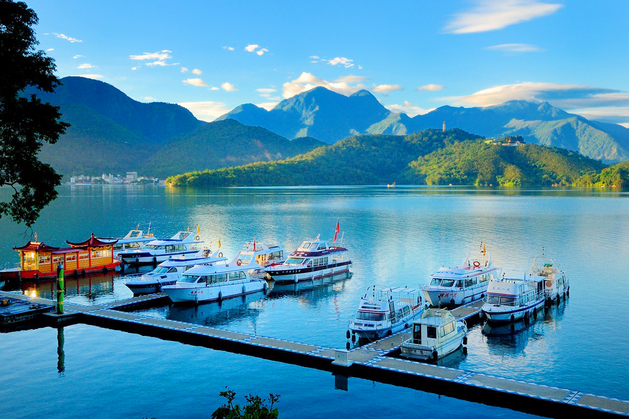 Boats on the water with mountains in the background  Description automatically generated