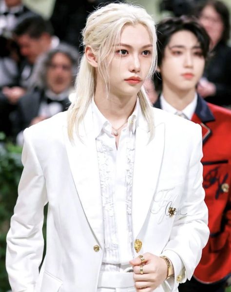 This contain an image of Stray Kids' Felix  with blonde hair wearing a white suit