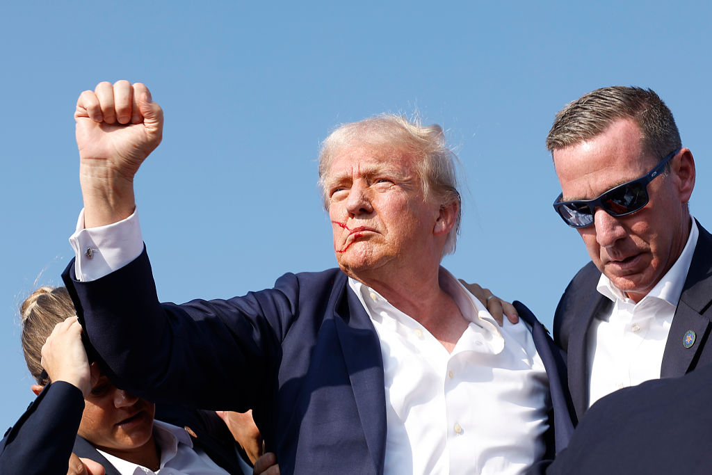 President Trump raises his fist after being shot in the ear while surrounded by Secret Service agents.
