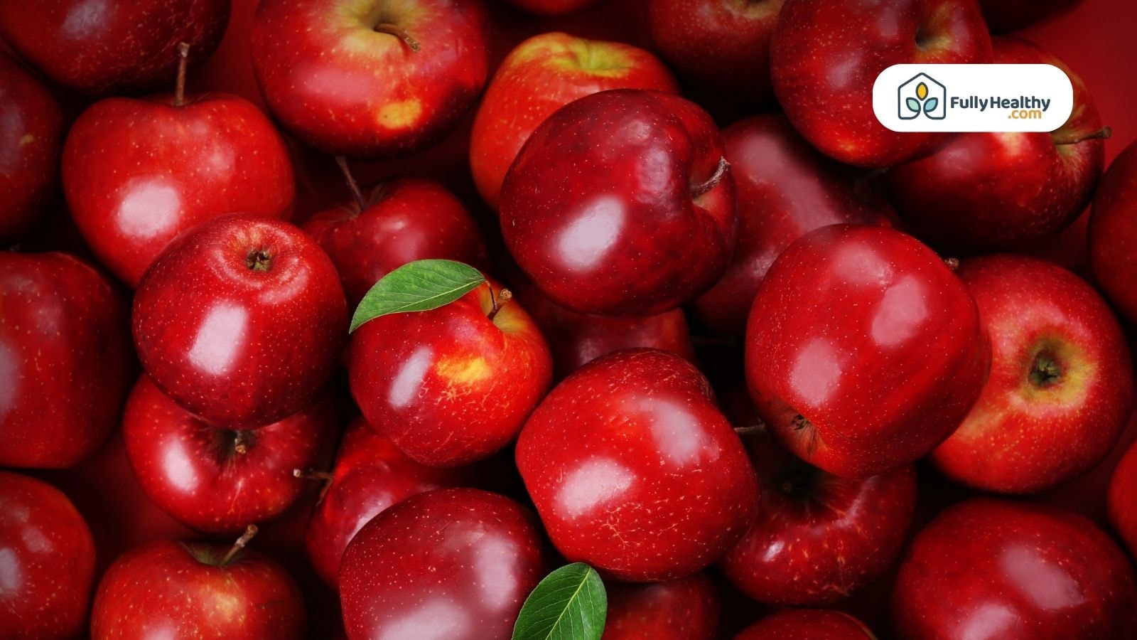 Fresh red apples with green leaves in harvest basket