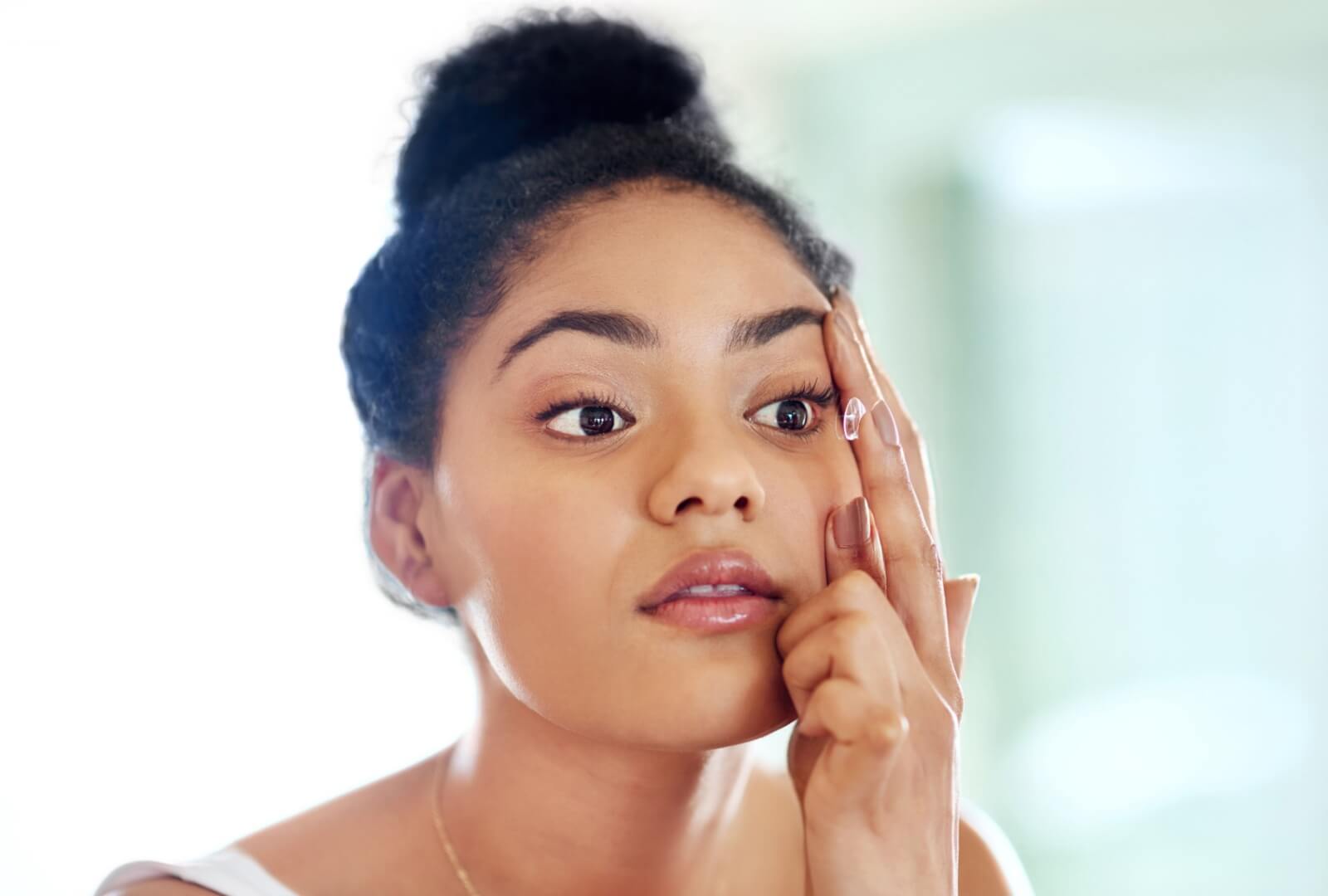 A young woman managing her keratoconus by inserting RGP contact lenses