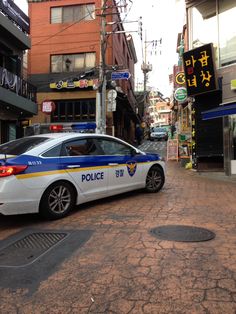  A police car parked on the side of a street next to tall buildings and shops