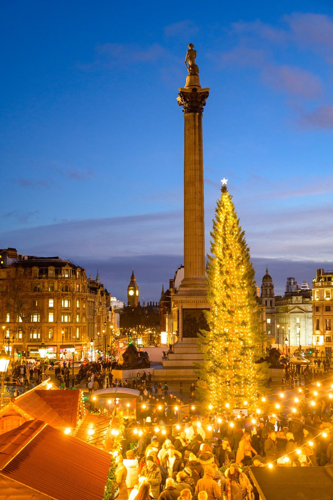 Trafalgar Square Christmas Market in London featuring festive stalls, holiday decorations, and visitors enjoying seasonal treats near the iconic Christmas tree