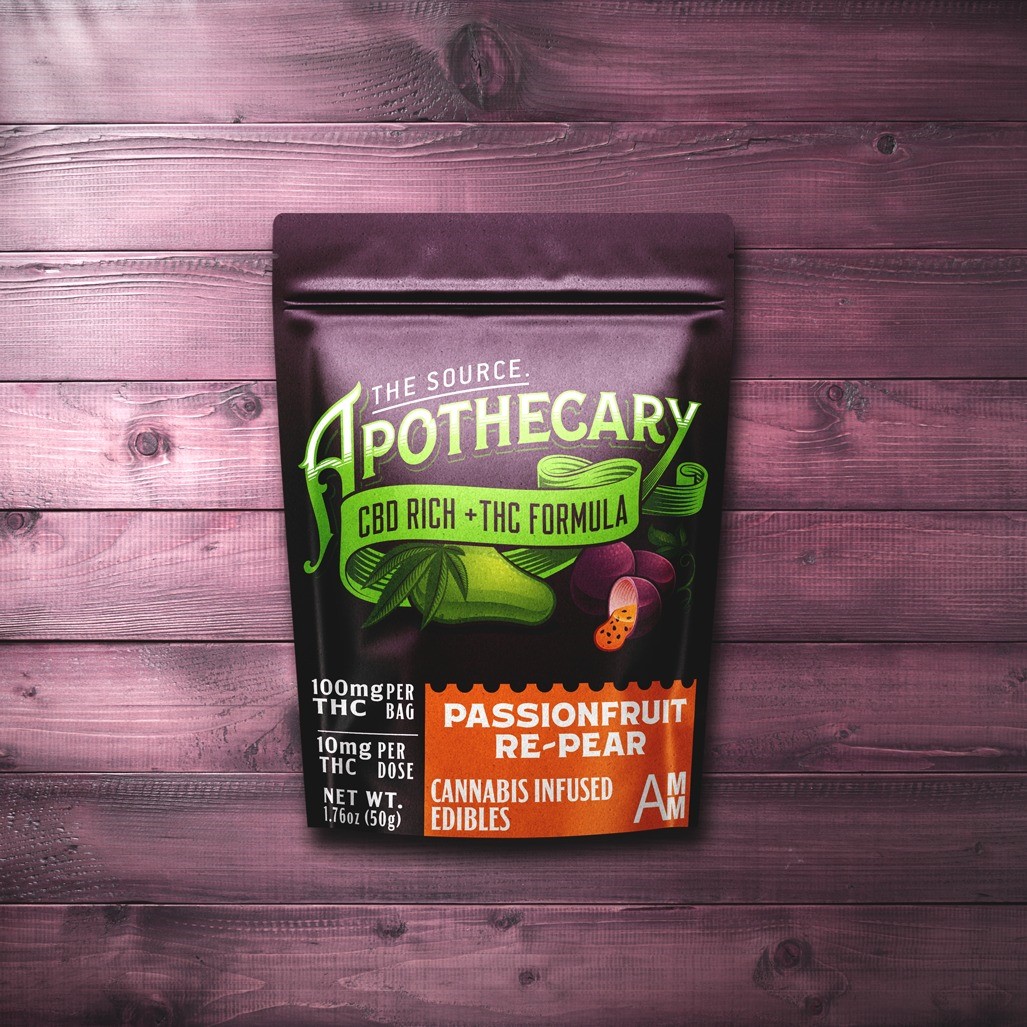 The Source Apothecary Cannabinoid Rich formula Passionfruit Re-Pear cannabis edibles are enriched with the alternative cannabinoid CBD plus THC. The eggplant purple colored, kraft paper packaging is shown from above and the background is multicolored wood.