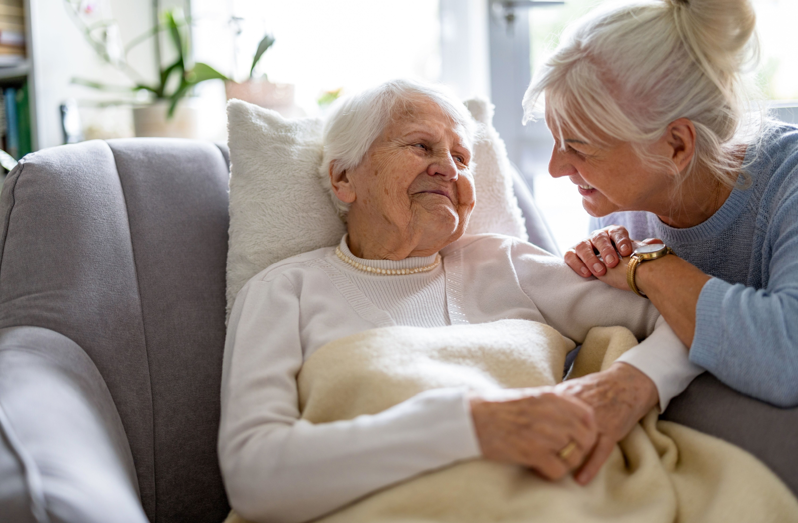 An adult child comforts their senior parent in memory care.