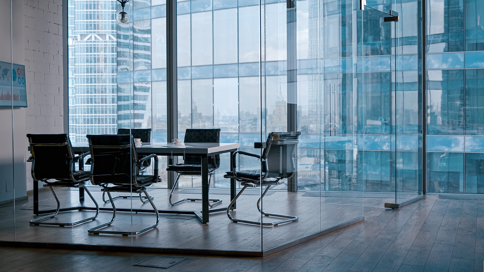 Meeting room with city view, rectangular tables and chairs around it. 