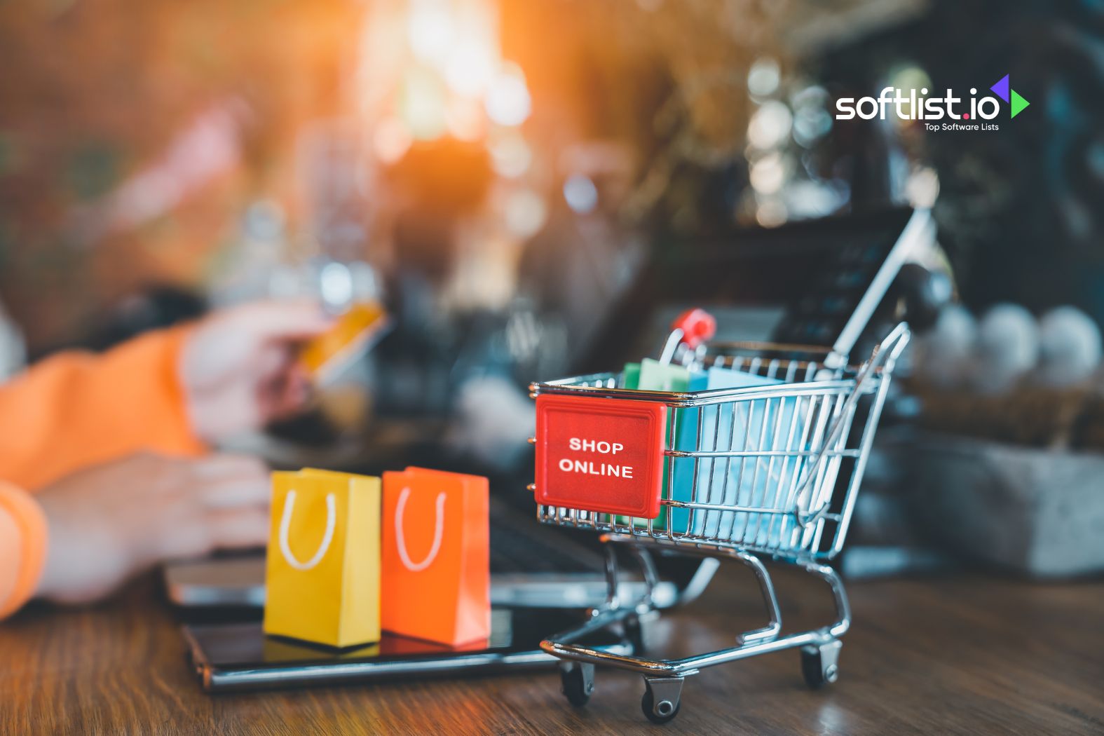 Shopping cart with small bags near a laptop, representing online shopping.