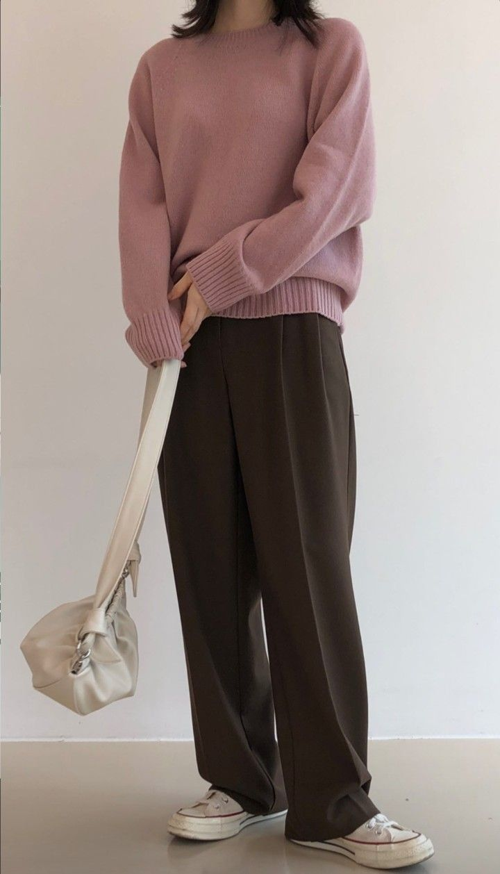 seorang wanita memakai sweater pink, celana cokelat, tas putih, dan sneaker putih