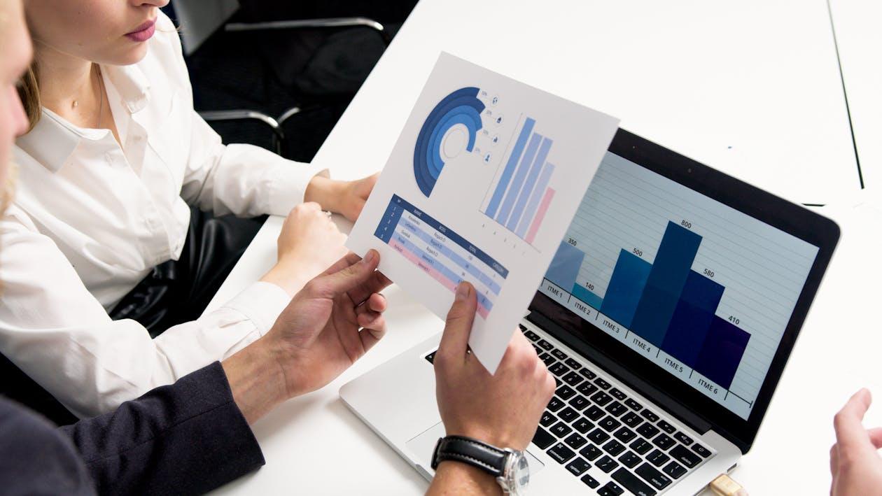 Free Business professionals discussing data charts and graphs in a modern office setting. Stock Photo