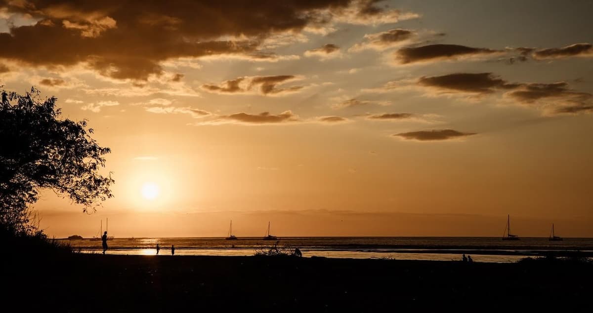 Sunset views from the Pangas Beach Club in Tamarindo with large sailboats in the water in the distance