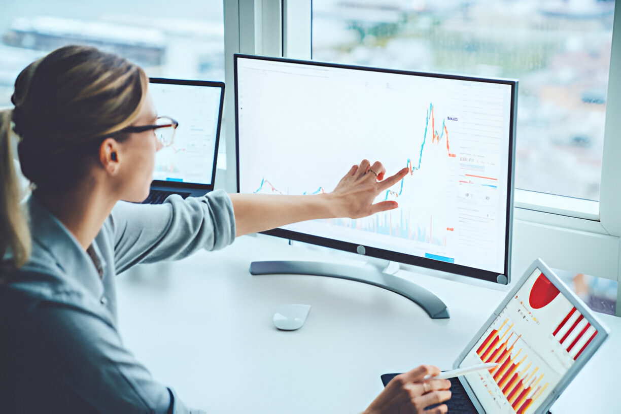 Financial analyst conducting vertical analysis by examining charts and graphs on multiple screens.