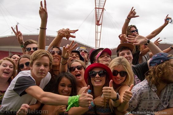 This contains an image of a group of young people standing next to each other with their hands up in the air