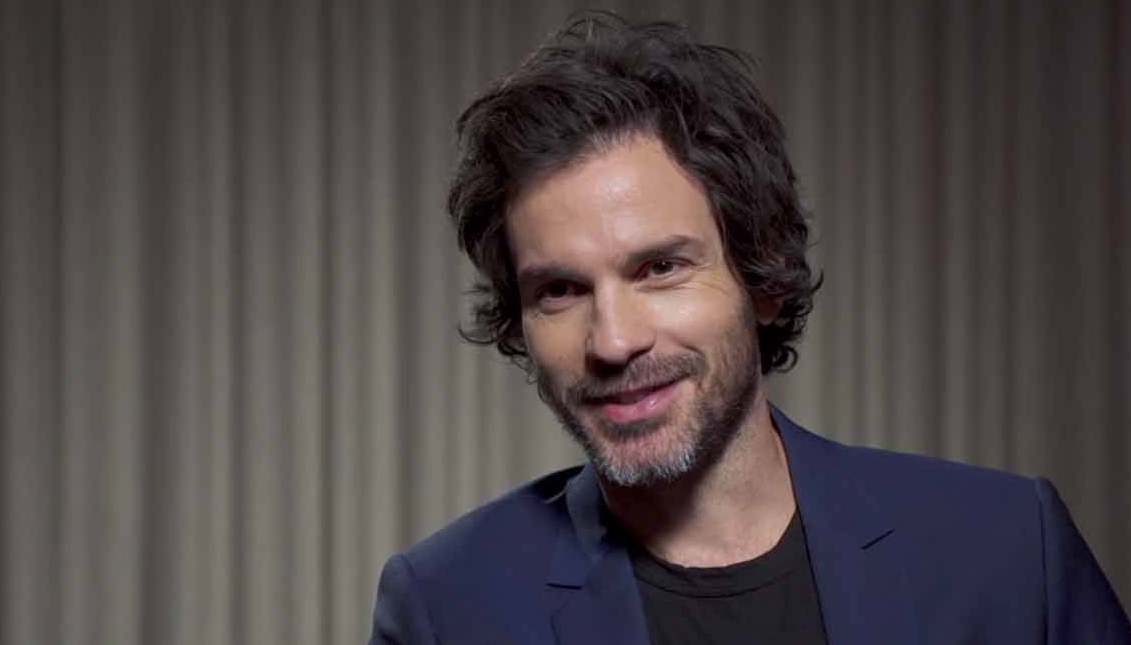 Santiago Cabrera en una entrevista, vistiendo un blazer azul oscuro y mostrando una expresión amigable.