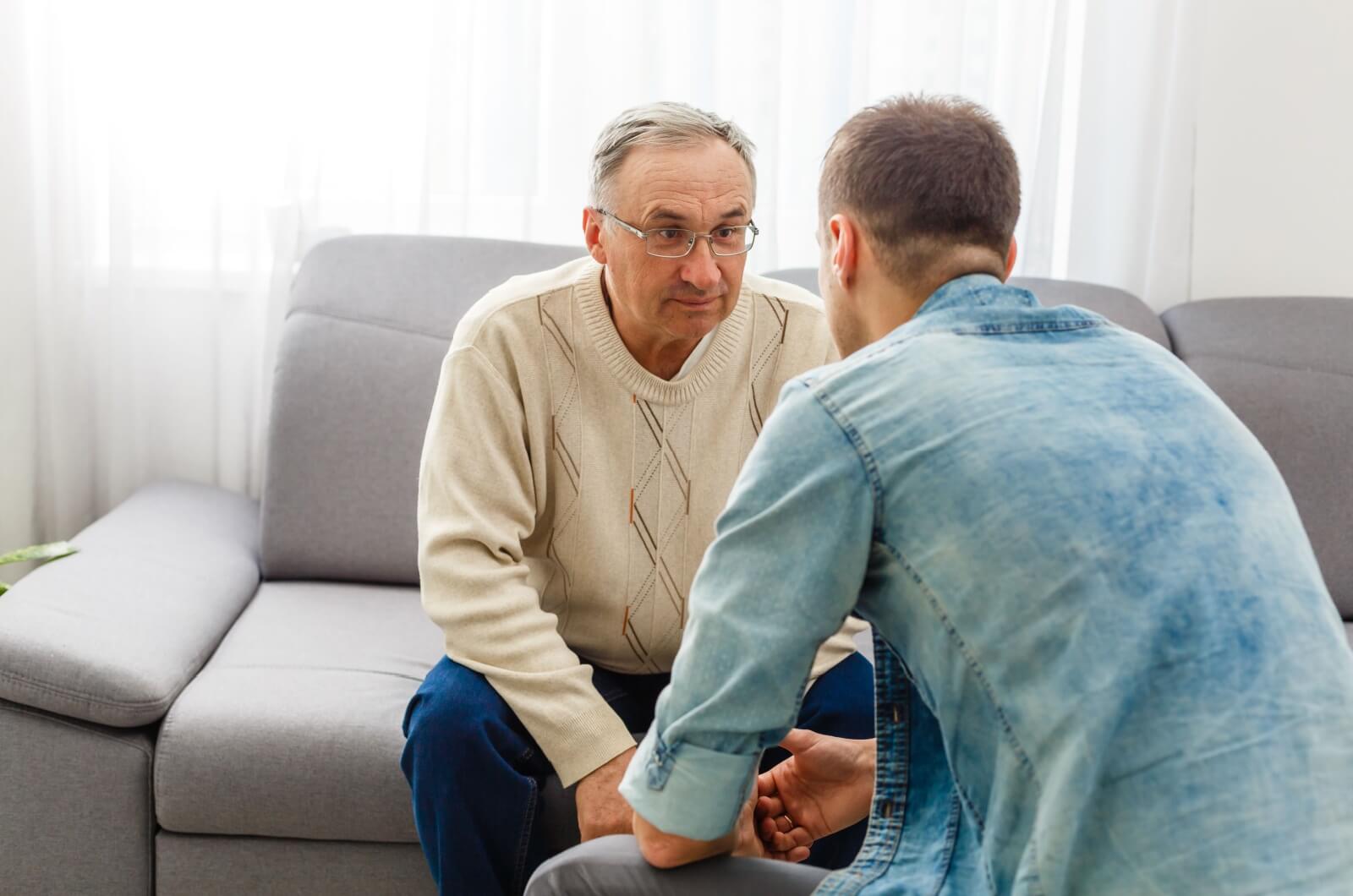 An adult child sitting across a parent and talking to them.