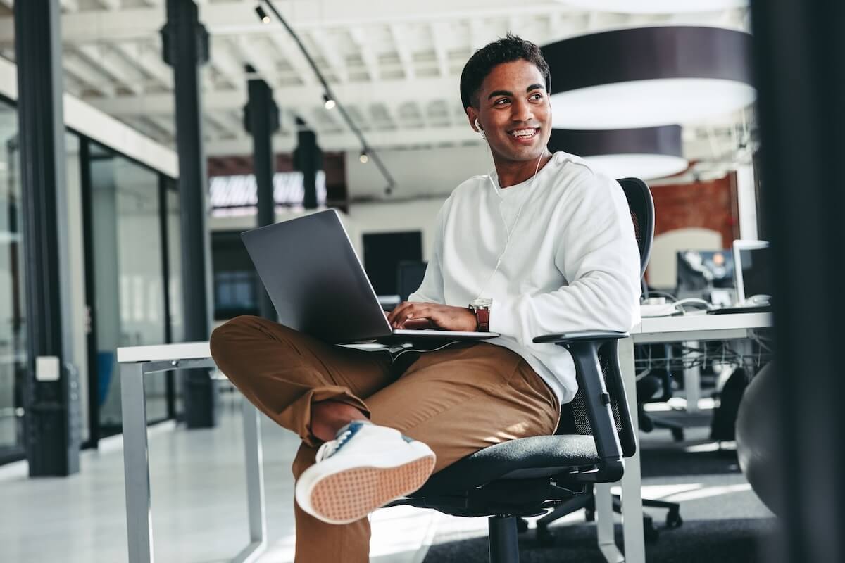 Employee happily wearing earphones while using his laptop