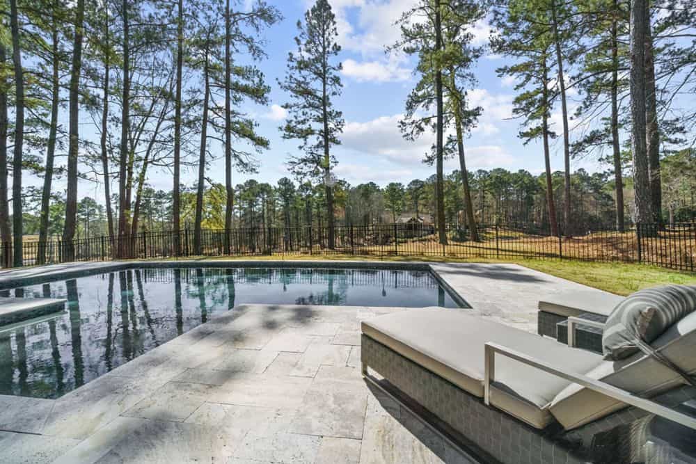 View of the home's backyard featuring a sparkling pool and expansive lawn.