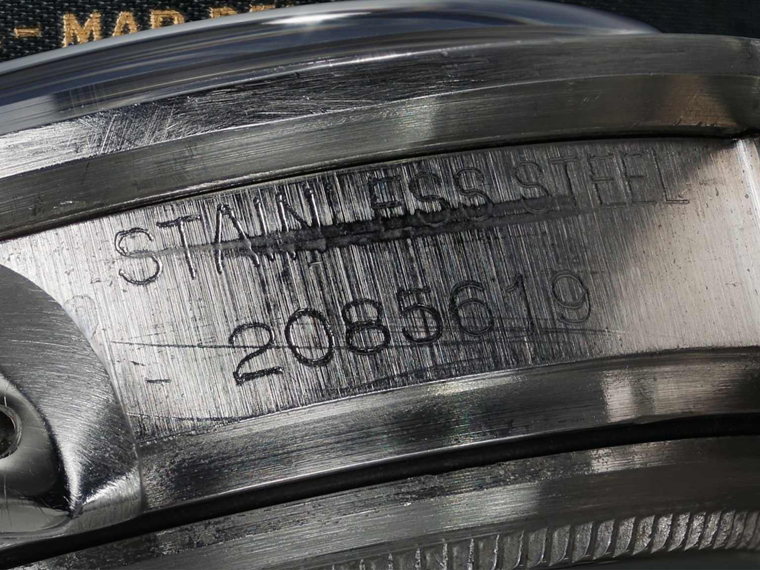 Close-up of a luxury watch case showing stainless steel engraving and serial number for authenticity verification