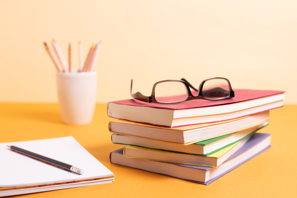 A stack of books with different colored covers sits on an orange surface, hinting at a crash course in knowledge.