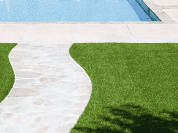 Artificial grass front yard idea with a stone walkway leading to a swimming pool in a clean, modern landscape.