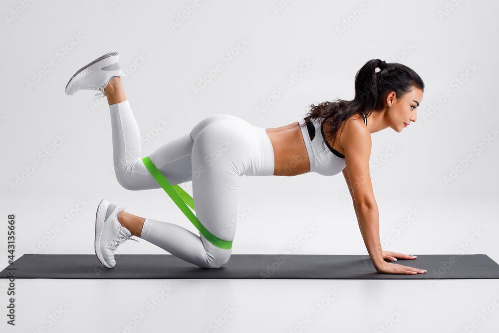 Fitness woman doing kickback exercise for glutes with resistance band on  gray background. Athletic girl working out donkey kicks. Stock Photo |  Adobe Stock