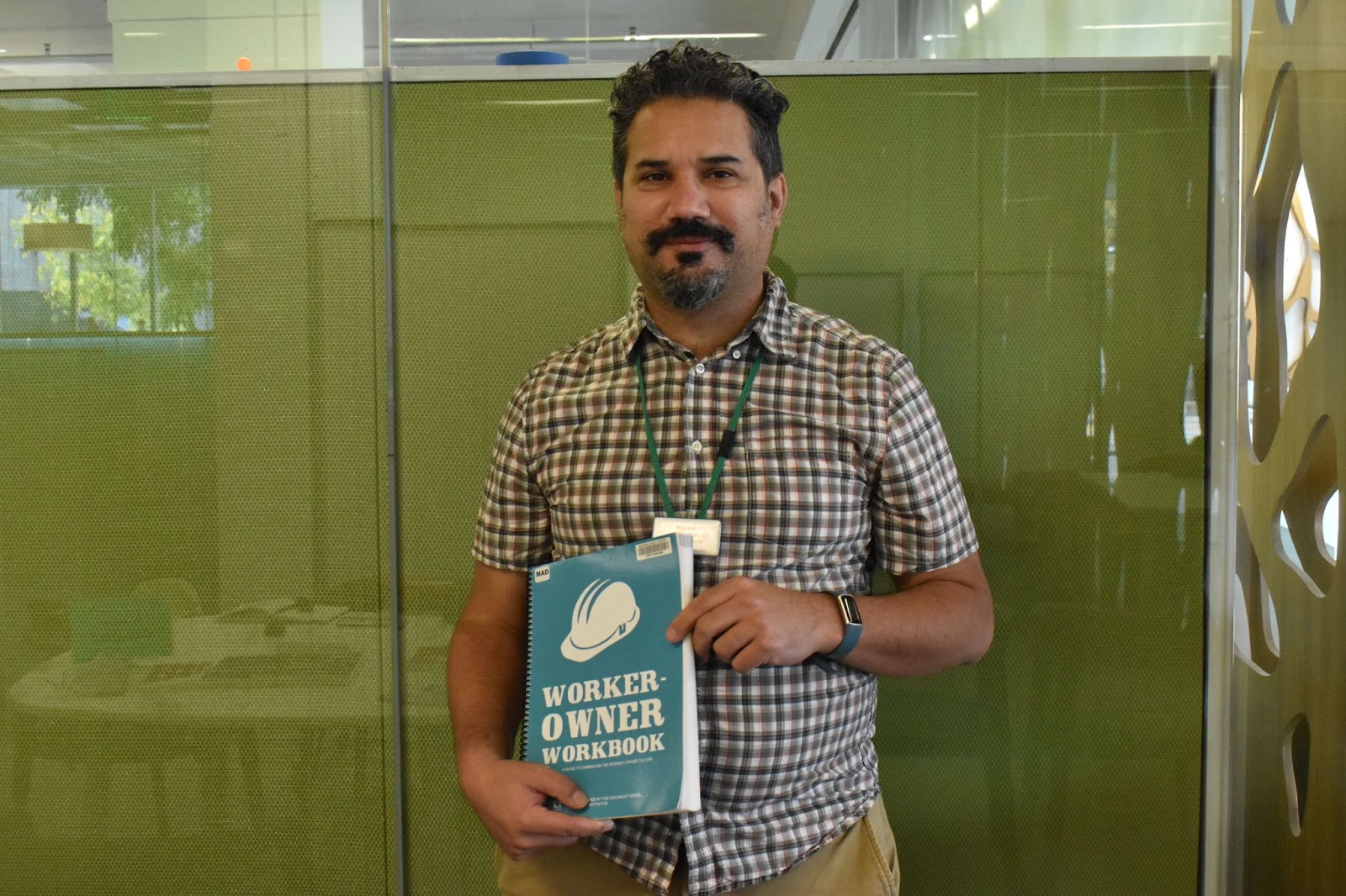 Man an smiling with a worker owner workbook. 