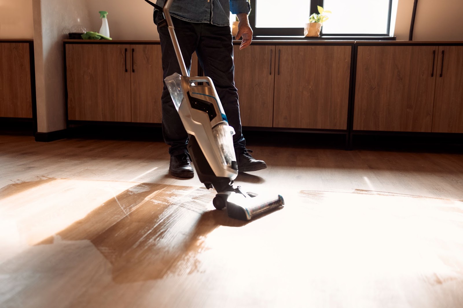 A man vacuums a hardwood floor.