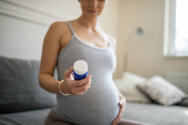 A pregnant lady holds the supplement bottle in her hand.