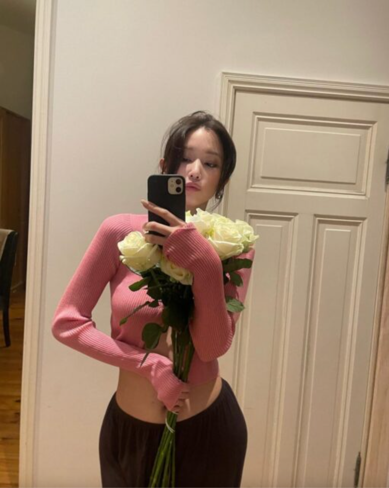 A picture of Jeon Jong Seo on a pink top and a black trouser holding a flower  