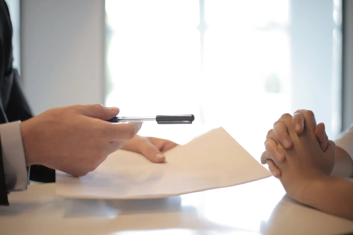 A hand holding a pen and paper