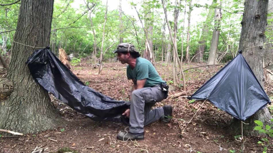 Garbage bag used as shelter by a man in a forest as a Survival Hacks Using Common Household Items 