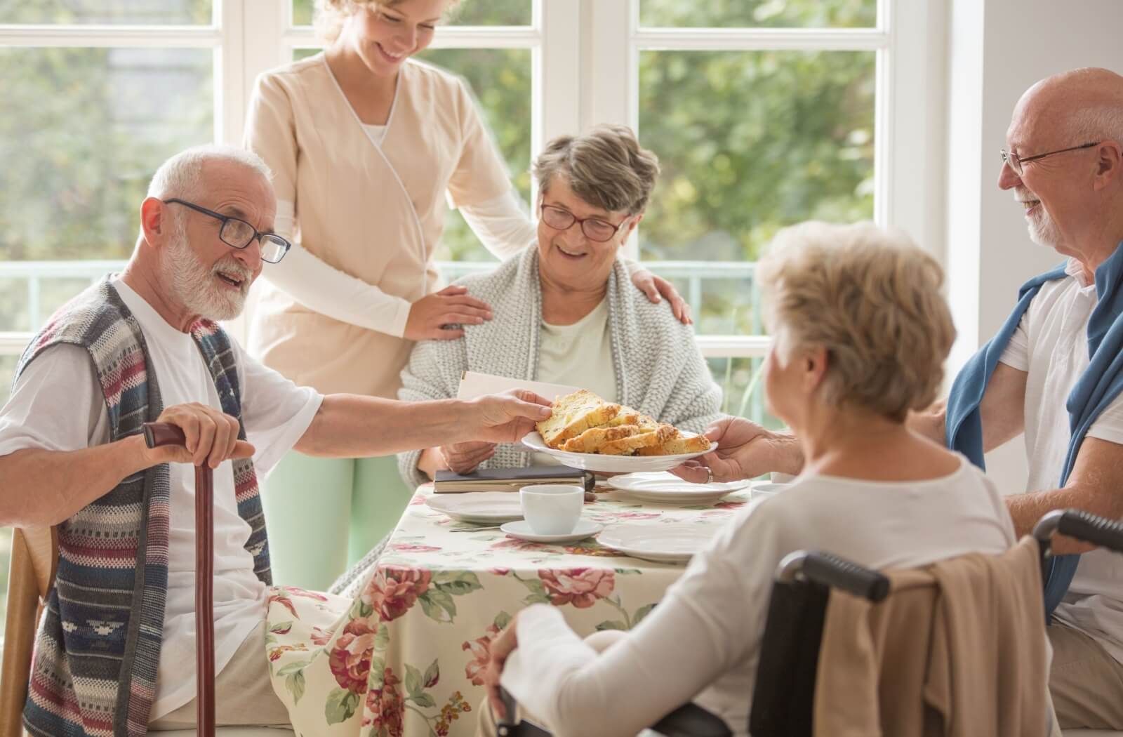 Lunch in an assisted living community with a group of seniors sharing a meal & chatting happily.