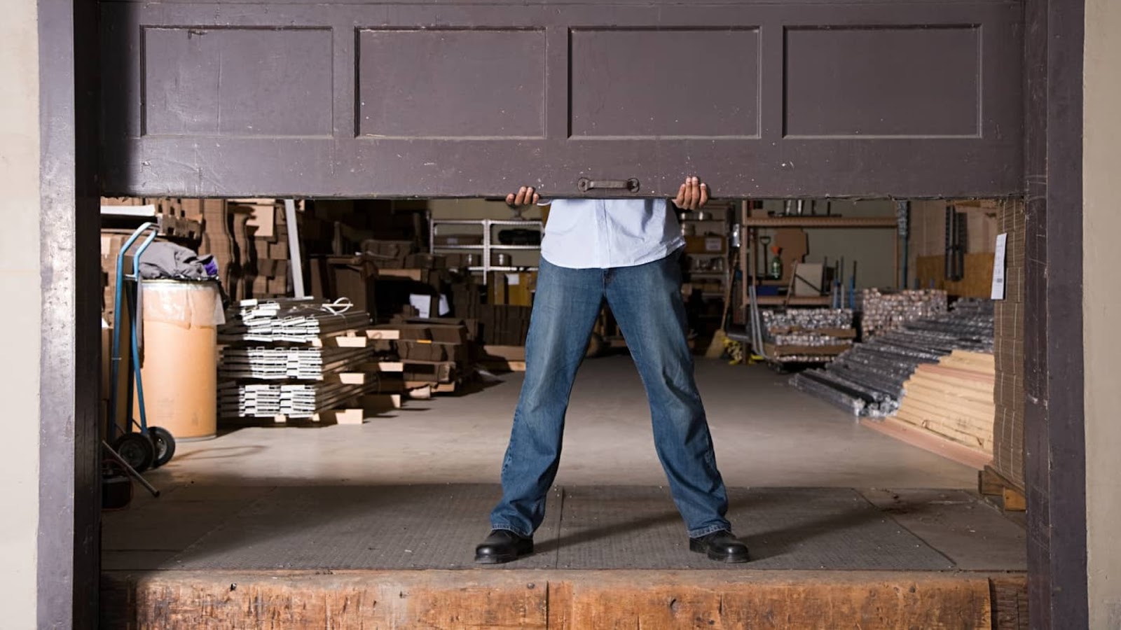 Partially opened garage door in a commercial workshop with visible materials inside.