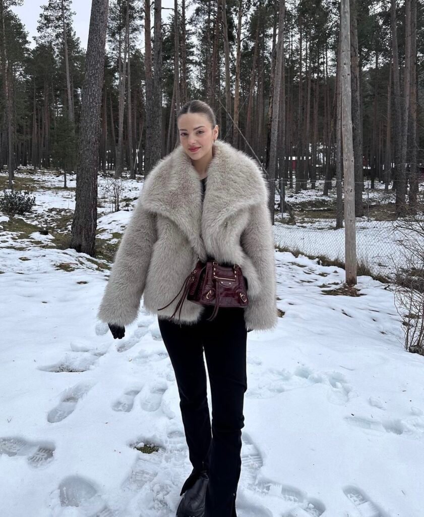 A cream faux leather and fur jacket and black flared plants.