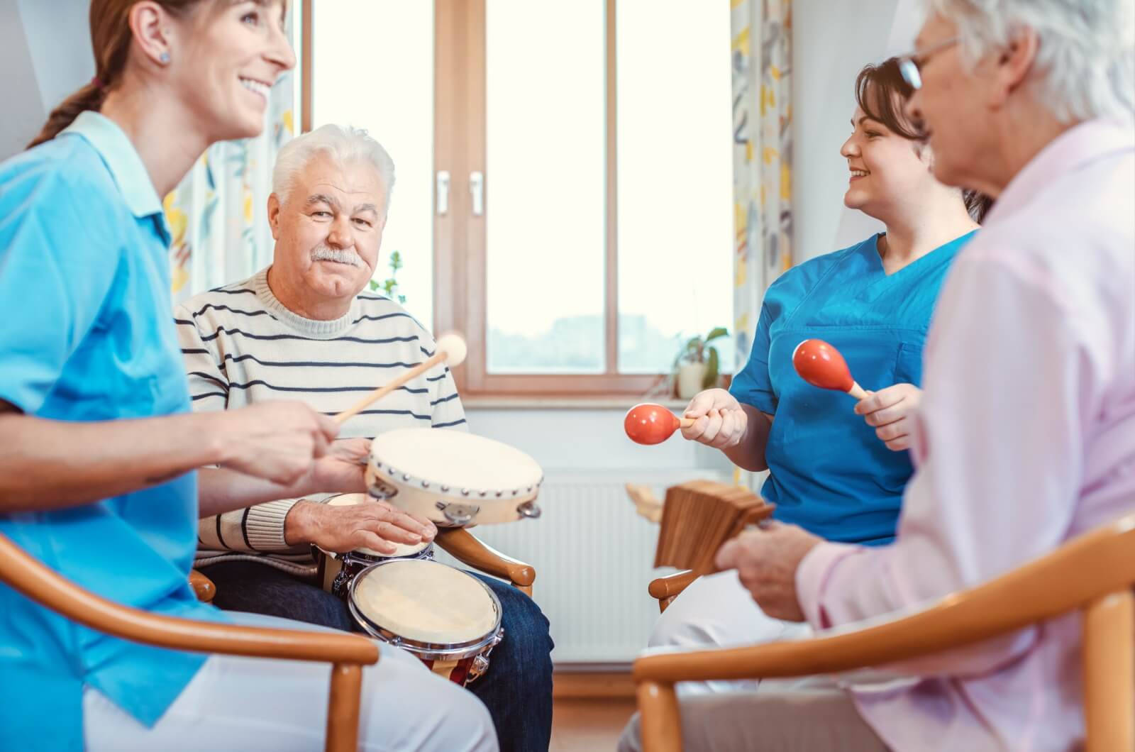 An older couple with staff members sitting and playing instruments.