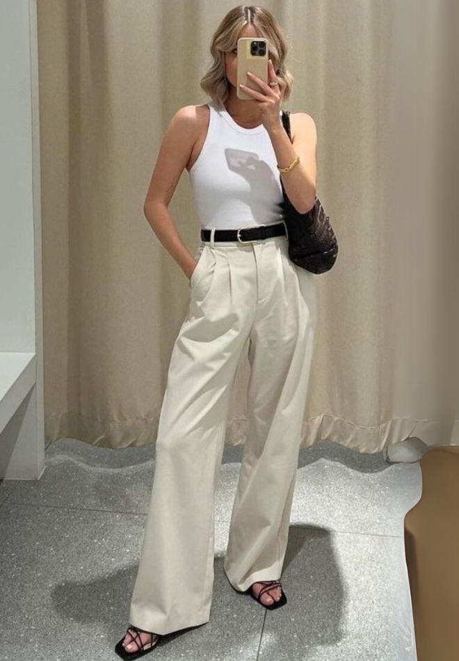 Wanita dengan trouser cream dan knitted top putih.